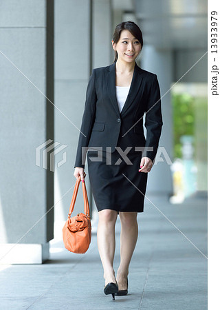 One young successful Chinese businesswoman walking along office building walkway 13933979