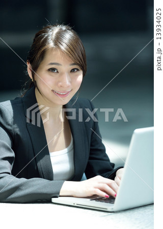 One young successful Chinese businesswoman using laptop along promenade 13934025