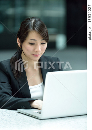 One young successful Chinese businesswoman using laptop along promenade One young successful Chinese businesswoman using laptop along promenade 13934027