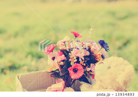 Bear and flower bouquet in brown box on green grass with natural 13934893