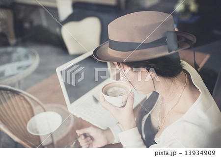 Asian woman drinking coffee and using computer in cafe. Asian woman drinking coffee and using computer in cafe. 13934909