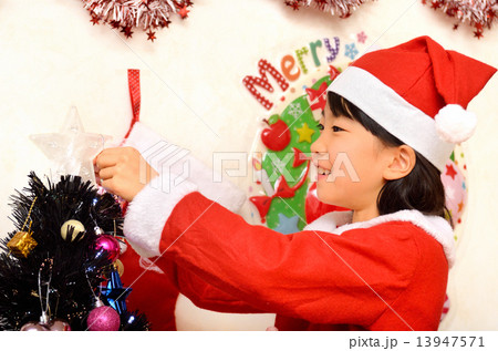 クリスマスツリーに飾り付けをするサンタクロース衣装の女の子 13947571