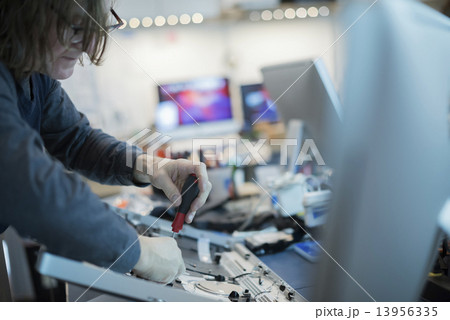 A m an using a screwdriver on the circuit boards of a computer. Repair technician. A m an using a screwdriver on the circuit boards of a computer. Repair technician. 13956335