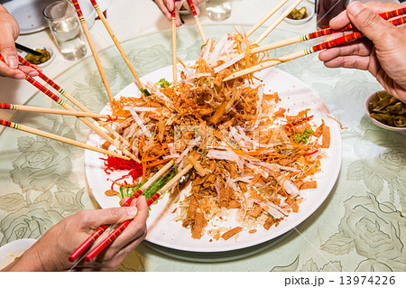 Mixing and tossing Yee Sang dish with chop sticks. Yee Sang is delicacy during Chinese New Year. 13974226