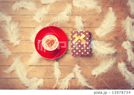 Coffee and feathers with gift on wooden background. Coffee and feathers with gift on wooden background. 13978734