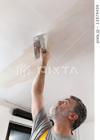 Worker repairing plaster at ceiling 13979499