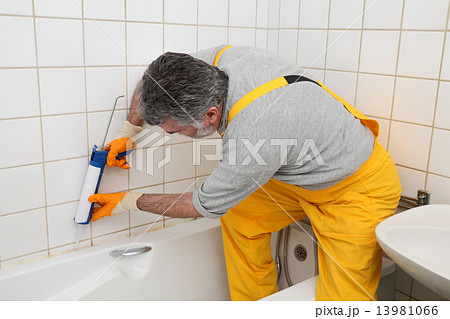 Worker caulking bath tube and tiles 13981066