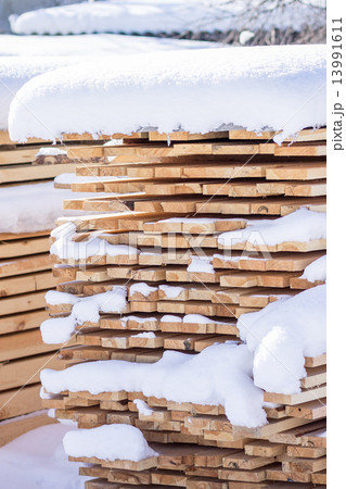 Stack of sawn planks covered with snow 13991611