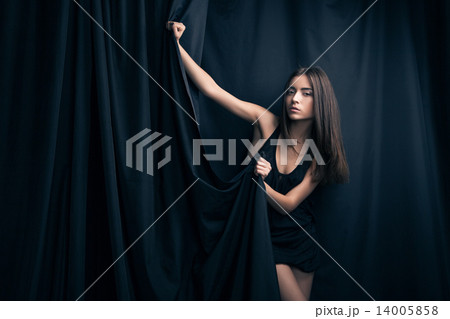Beautiful fashion model posing and foldinng stage curtains. 14005858