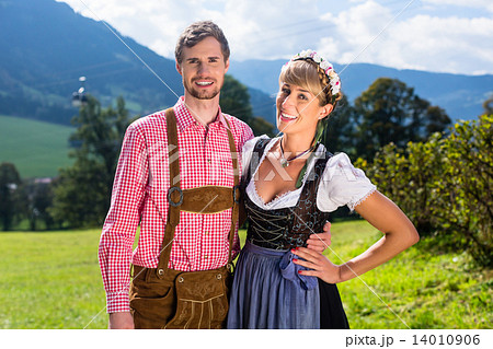 Couple in Tracht standing on meadow in alp mountains 14010906