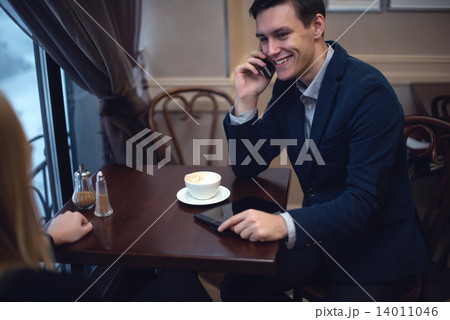 Handsome entrepreneur enjoying his launch in a cafe talking with someone by the phone. Handsome entrepreneur enjoying his launch in a cafe talking with someone by the phone. 14011046