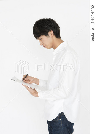 何かを記入する白いシャツの若い男性 何かを記入する白いシャツの若い男性 14014458