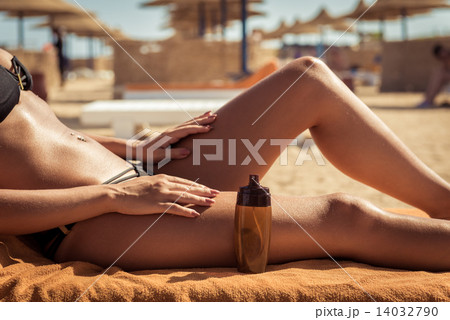Sensuous slim woman applying suntan oil 14032790