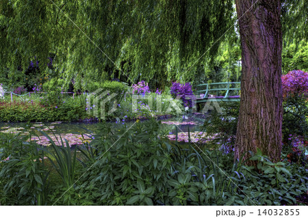 A bridge passes by a flower edged pond in Monet's Garden 14032855