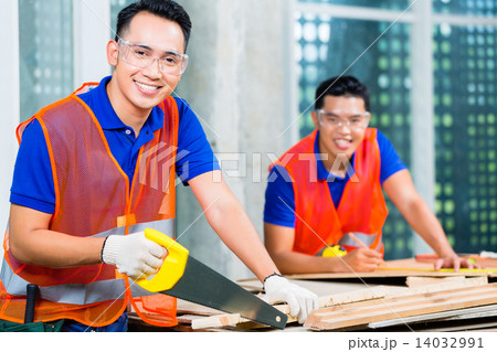 Builder sawing a wood board of building or construction site 14032991