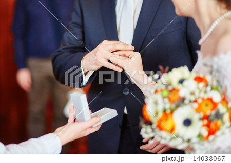 Bride putting the ring on groom's finger 14038067