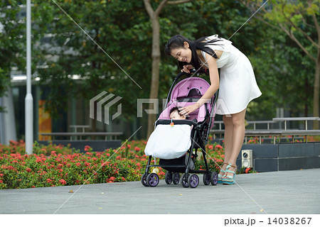 Chinese mother pushing baby stroller in a park Chinese mother pushing baby stroller in a park 14038267