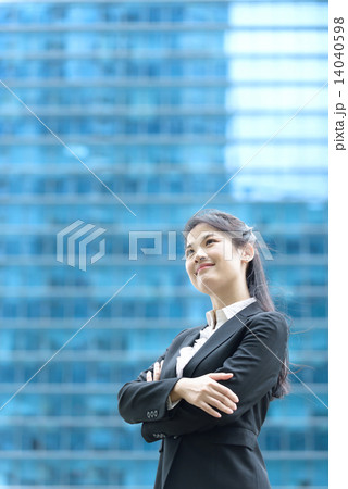 Successful chinese businesswoman standing in front of blue glass office building 14040598