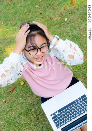 Cute girl is happy with notebook on grass 14044048