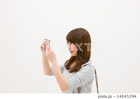 スマートフォンで何かを撮ろうとしている笑顔の若い女性 スマートフォンで何かを撮ろうとしている笑顔の若い女性 14045294