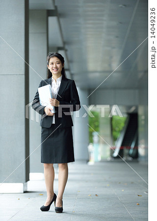 Successful chinese businesswoman holding document along office building walkway 14049236