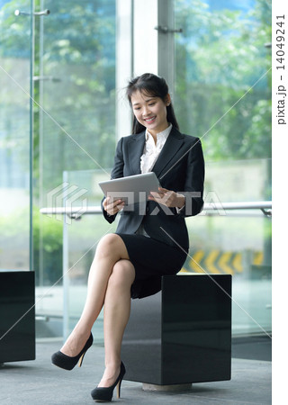 Successful chinese businesswoman using tablet iPad sitting along office promenade 14049241