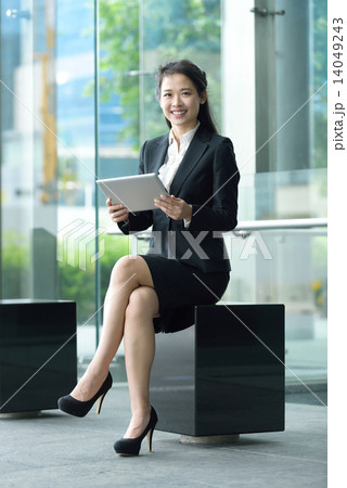 Successful chinese businesswoman using tablet iPad sitting along office promenade Successful chinese businesswoman using tablet iPad sitting along office promenade 14049243