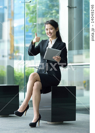 Successful chinese businesswoman giving thumb up gesture using tablet iPad sitting along promenade Successful chinese businesswoman giving thumb up gesture using tablet iPad sitting along promenade 14049246