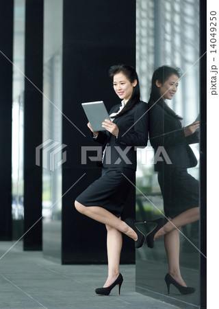 Successful chinese businesswoman using tablet iPad along office promenade 14049250