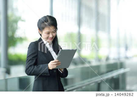 Successful chinese businesswoman using tablet iPad along office promenade 14049262