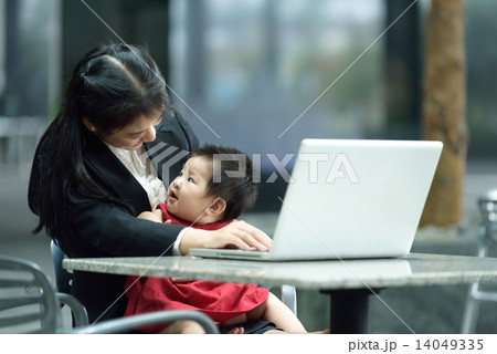 Chinese working mother taking care of daughter while using laptop Chinese working mother taking care of daughter while using laptop 14049335
