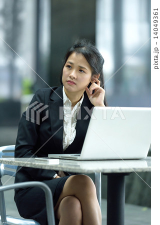 Chinese businesswoman in thoughts while using laptop along office promenade 14049361