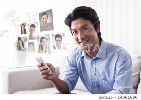 Composite image of happy man sitting on couch texting on phone 14061680
