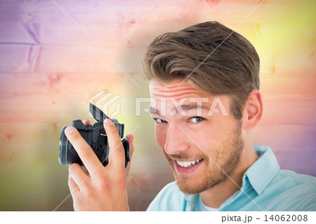 Composite image of handsome young man holding digital camera 14062008