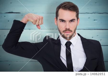 Composite image of businessman tensing arm muscle and looking at 14062051