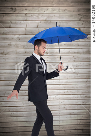 Composite image of concentrated businessman holding umbrella whi 14062199