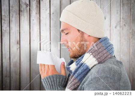 Composite image of handsome man in winter fashion blowing his no Composite image of handsome man in winter fashion blowing his no 14062223