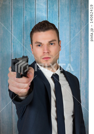 Composite image of serious businessman pointing a gun Composite image of serious businessman pointing a gun 14062419