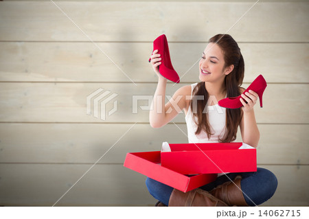 Composite image of content brunette holding red shoes 14062715