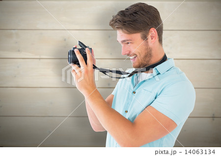 Composite image of handsome young man holding digital camera Composite image of handsome young man holding digital camera 14063134