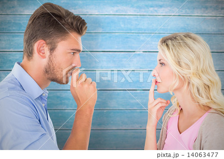 Composite image of young couple staying silent with fingers on l Composite image of young couple staying silent with fingers on l 14063477