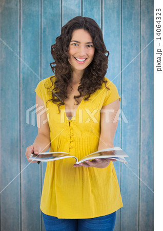 Composite image of cheerful curly haired brunette reading magazi Composite image of cheerful curly haired brunette reading magazi 14064323