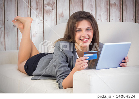 Composite image of woman doing online shopping with tablet and c 14064524