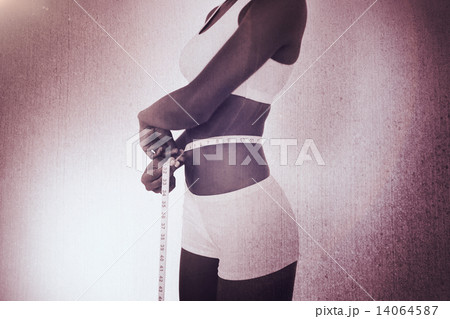 Composite image of young woman measuring her waist during diet 14064587