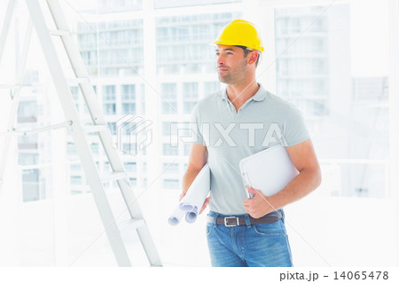 Handyman with blueprints and clipboard in office Handyman with blueprints and clipboard in office 14065478
