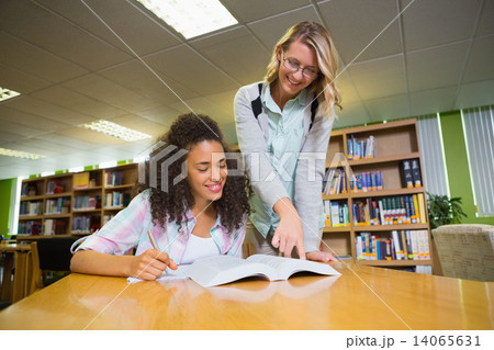 Student getting help from tutor in library 14065631