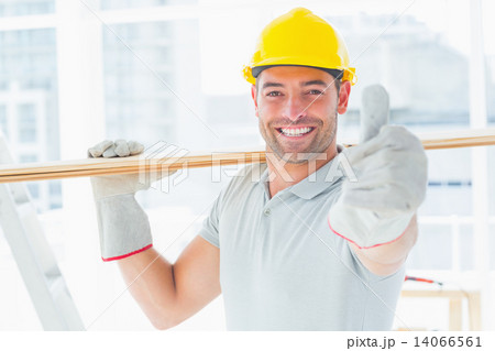 Handyman carrying wood while gesturing thumbs up Handyman carrying wood while gesturing thumbs up 14066561
