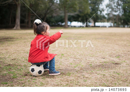 サッカーボールに座る少女の写真素材
