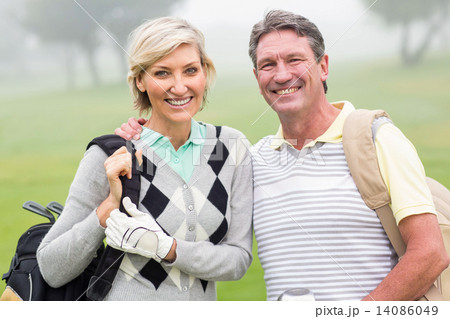 Golfing couple smiling and holding clubs 14086049