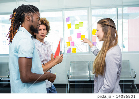 Creative team pointing at adhesive notes in office 14086901